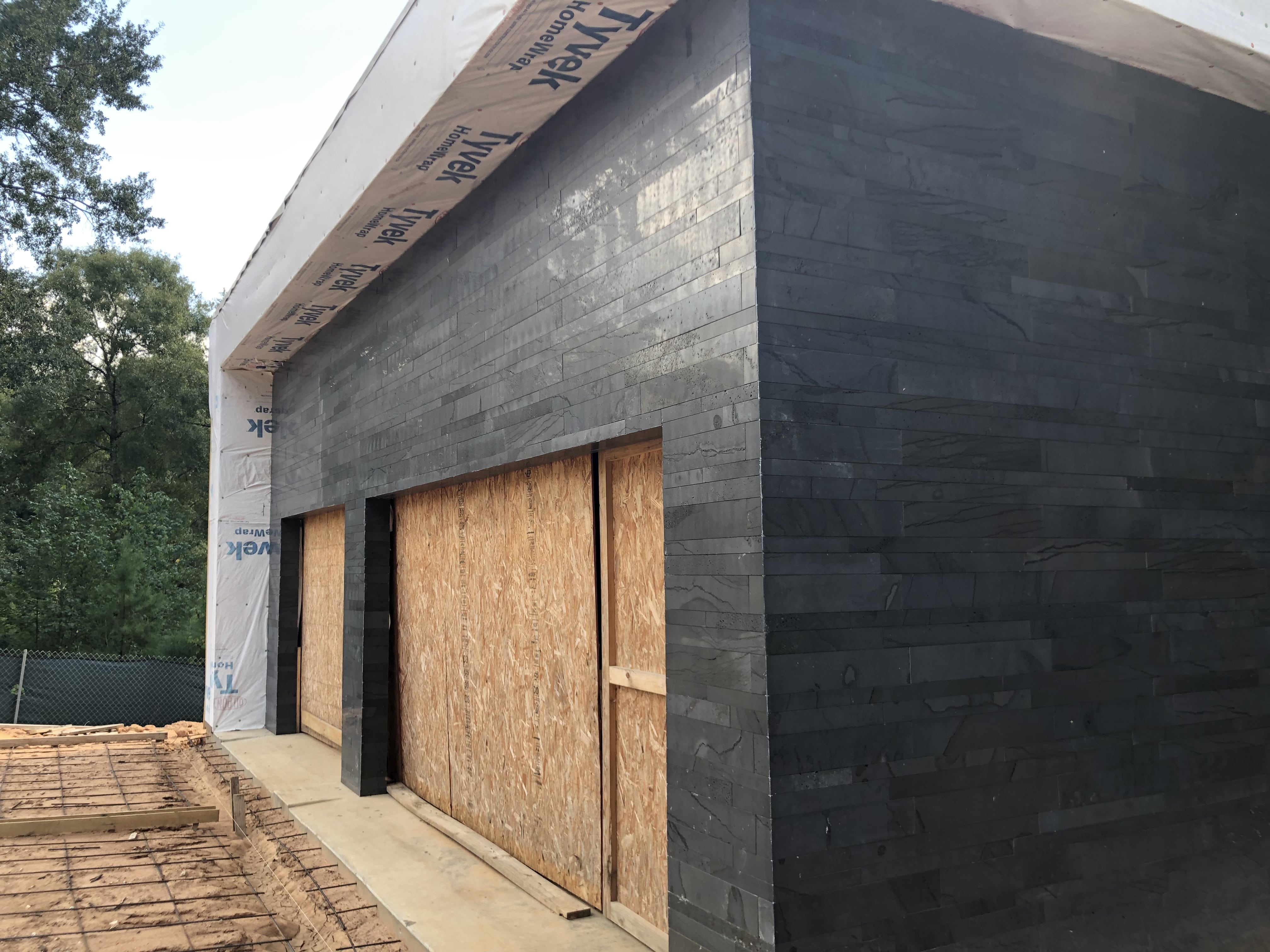 Norstone Graphite Planc Large Format Tile on a residential wall under construction showing an outside corner created with miter cuts